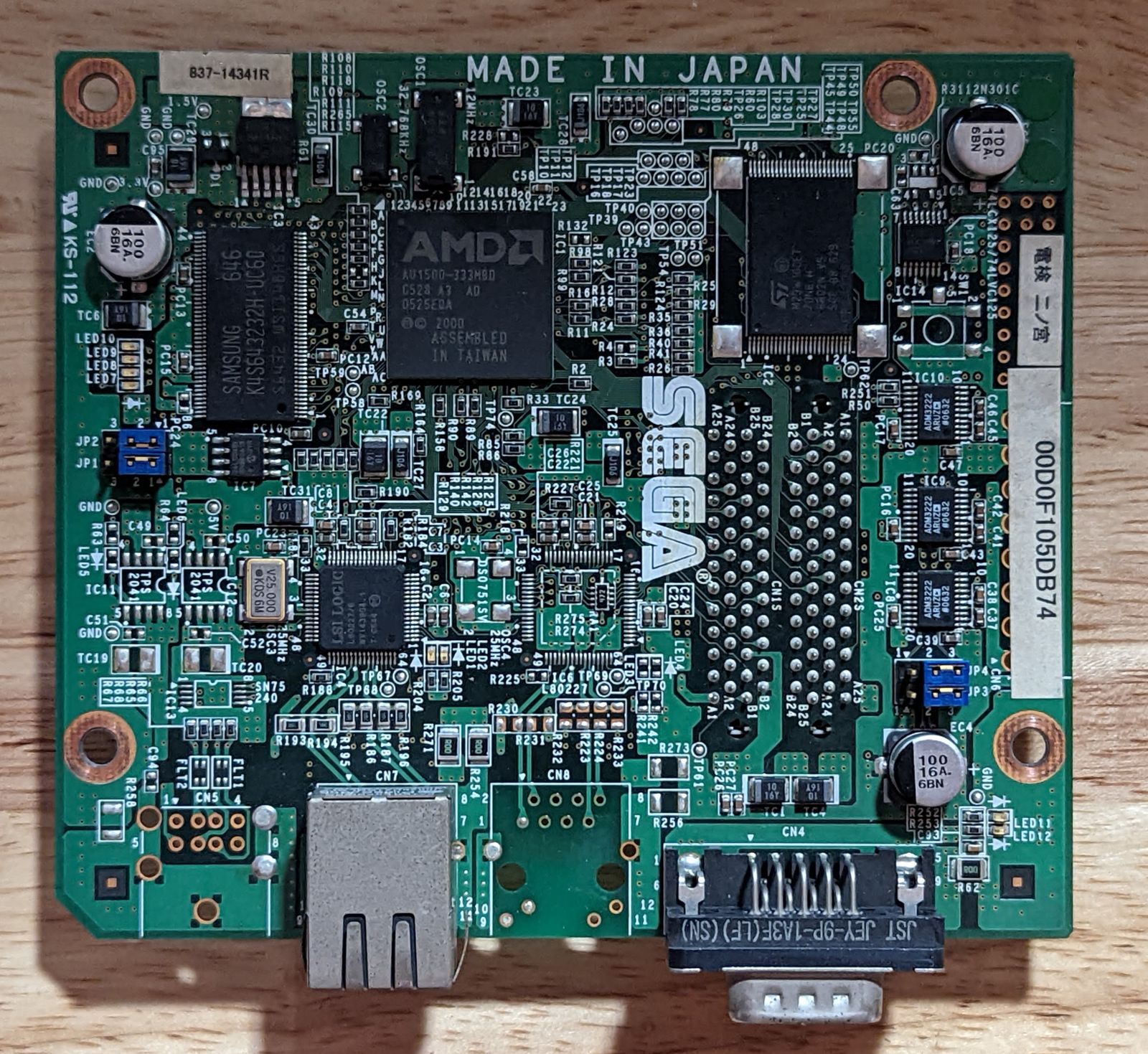 Photo of Triforce Type 3 network interface card, maybe? The board is pretty densely populated, though there are two unpopulated connectors. One of the unpopulated connectors looks like it would've been a second RJ45 connector.