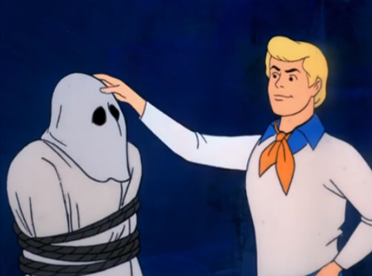 A screenshot of Fred Jones from Scooby Doo imminently unmasking a perpetrator.